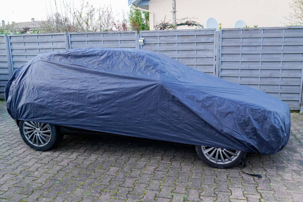 car parked under blue colored protective cover jacket outside